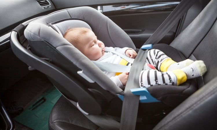 младенец лежит в автокресле на переднем сиденье автомобиля против направления движения