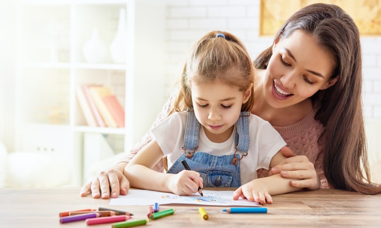 девочка рисует цветными карандашами рядом с мамой