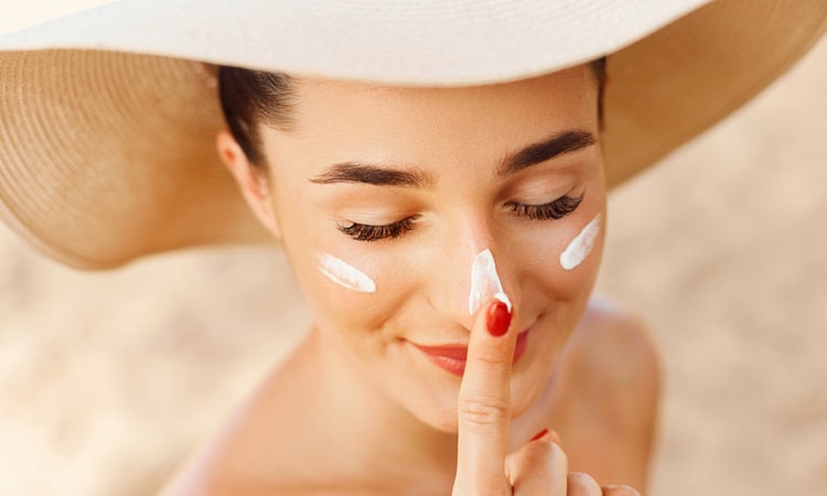 женщина наносит солнцезащитный крем на лицо