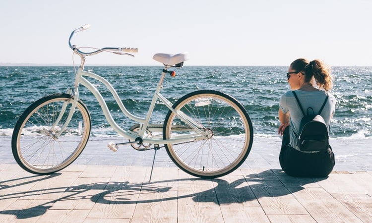sieviete atbrauca ar velosipedu uz pludmali