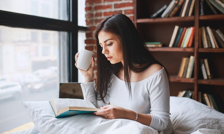 женщина утром перед работой читает в кровати книгу