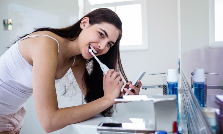 sieviete tira zobus ar elektrisko zobu birsti