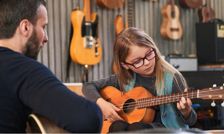 отец учит дочку играть на гитаре