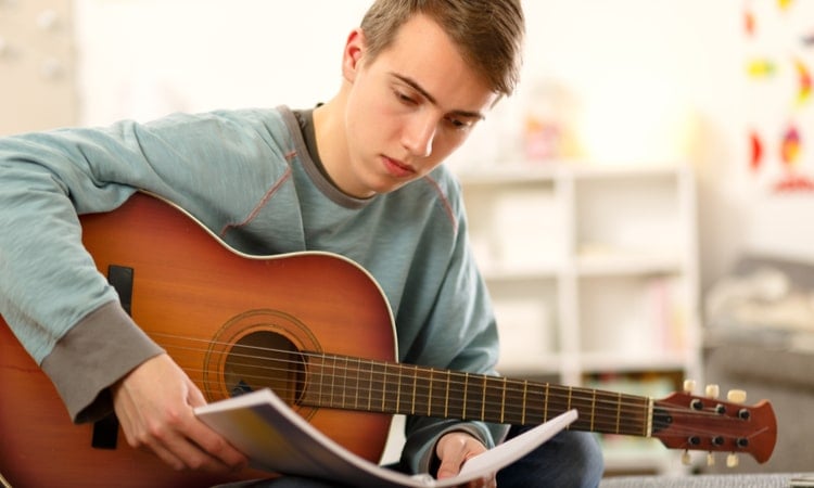 мужчина играет на гитаре и читает ноты