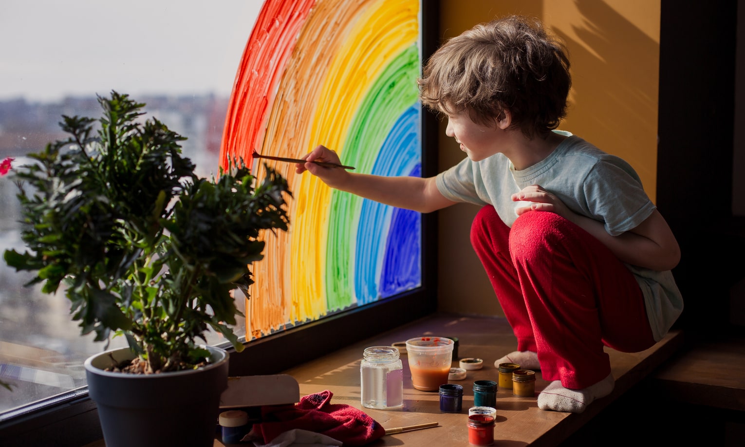 мальчик рисует красками на окне