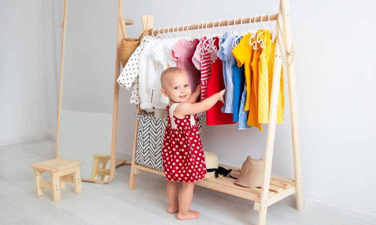 маленький ребенок выбирает одежду в шкафу